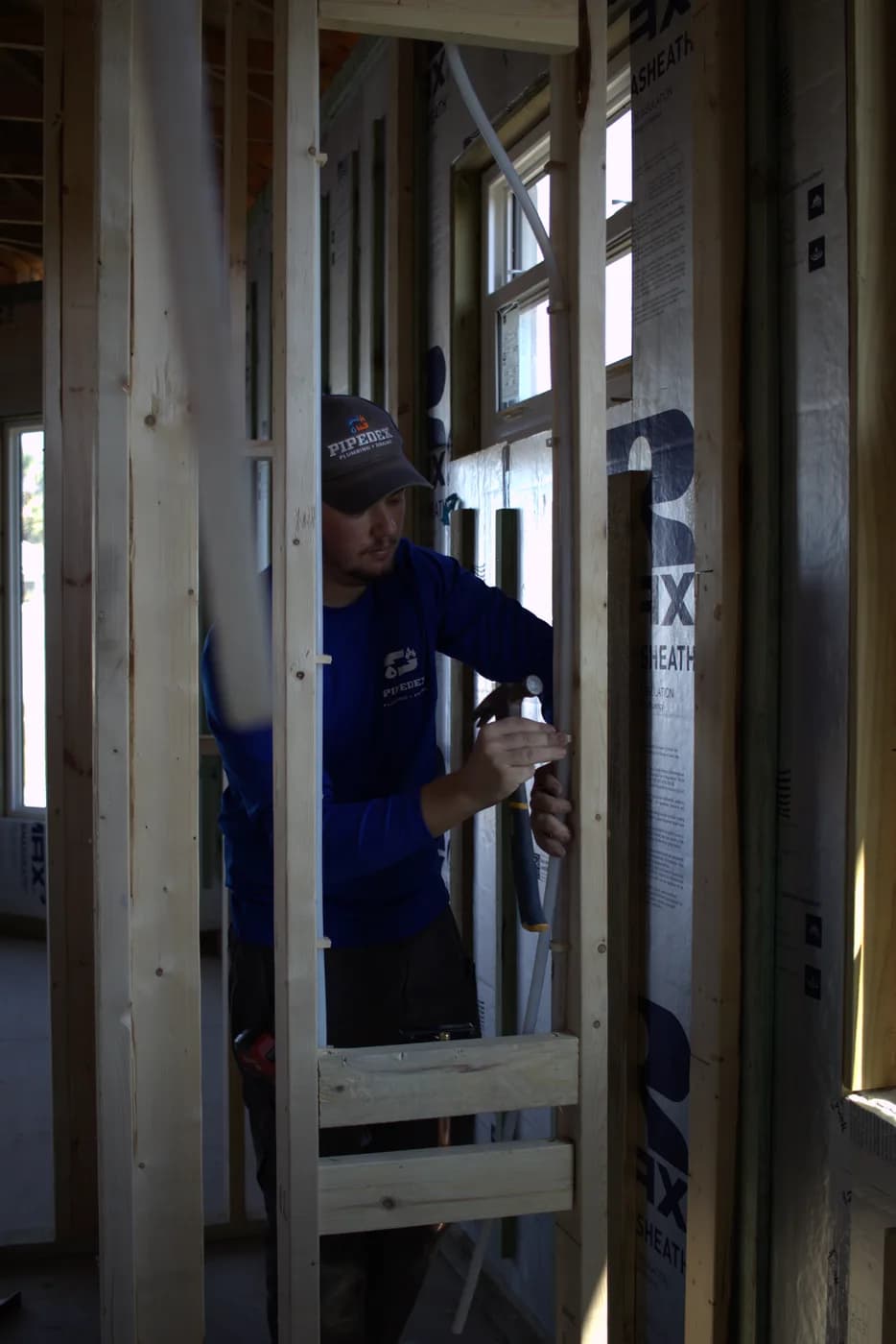 Pipedex technician roughing in plumbing on a job site